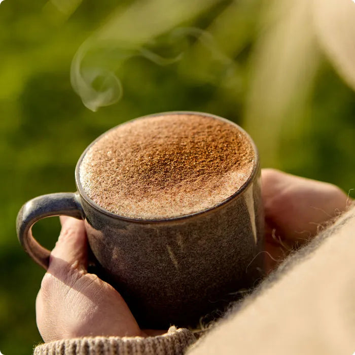 Steaming cup of Chai Masala tea made with plant-based milk and sprinkled spices.